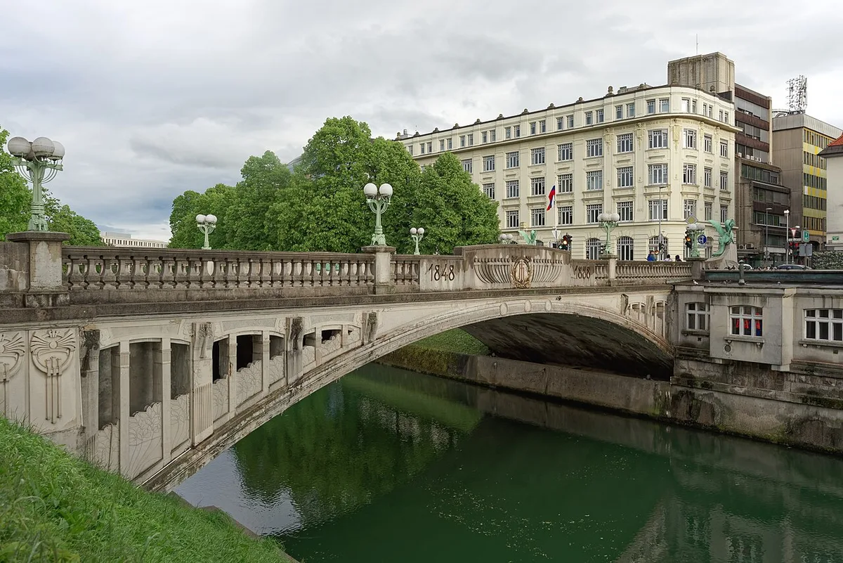 De historische Draakbrug van Ljubljana over de Ljubljanica rivier met het kasteel op de heuvel erboven